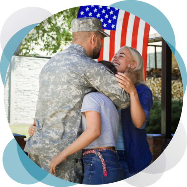 A man in fatigues hugging an older woman.