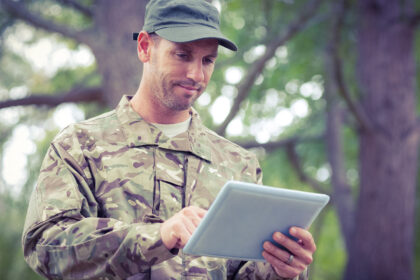 A man in camouflage uniform holding an ipad.